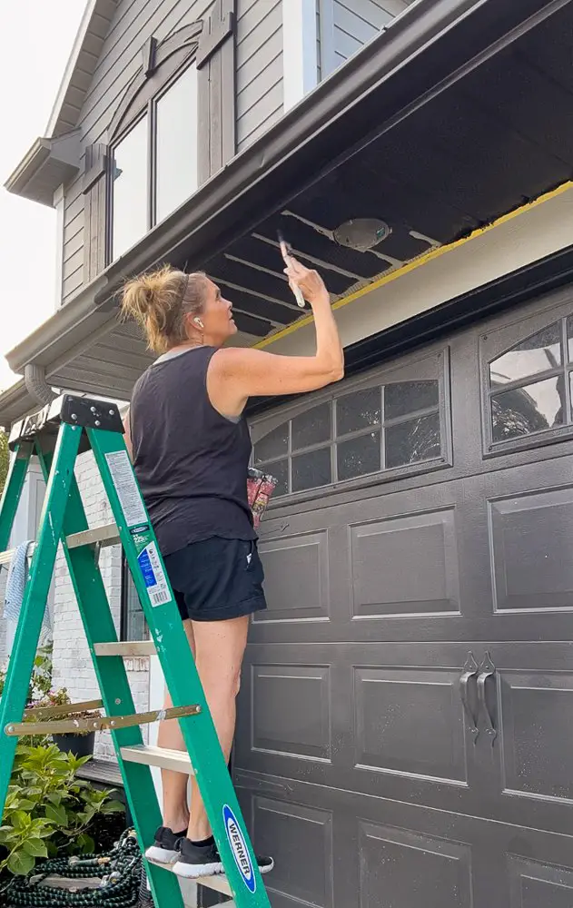 Girl painting gutters black.