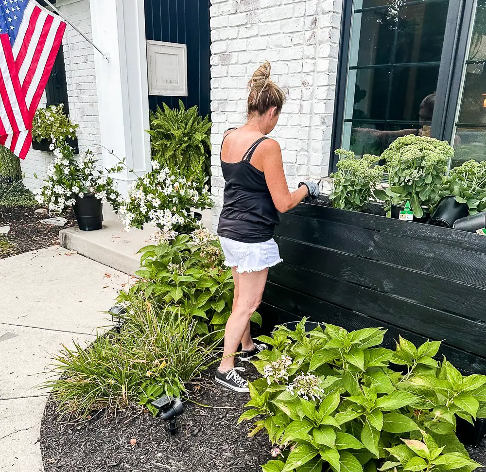 Girl in front of black planter for curb appeal ideas.