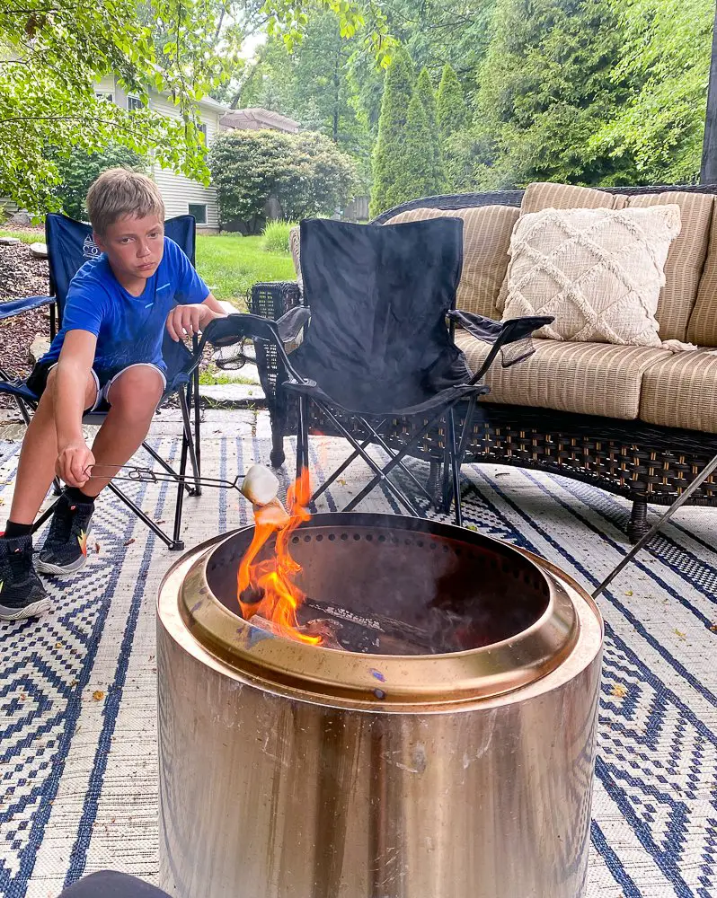 A boy roasting a marshmallow over a firepit