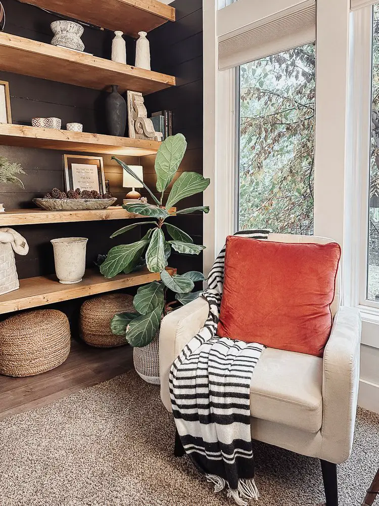 floating shelves with a neutral color chair and red pillow