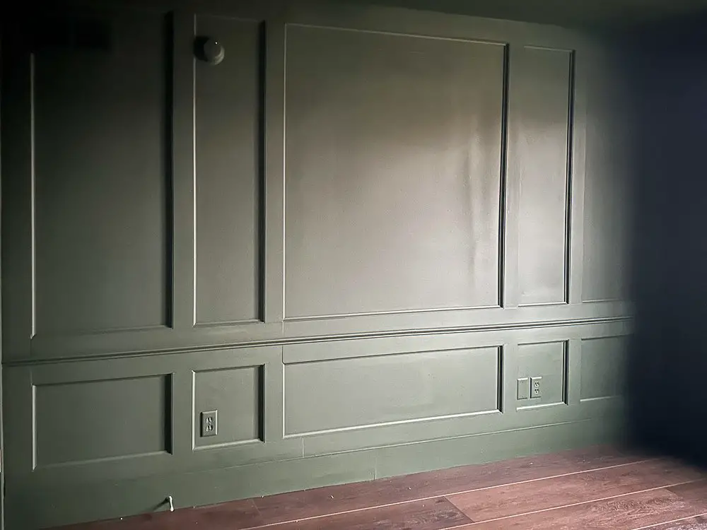 Millwork accent wall painted a deep moody green
