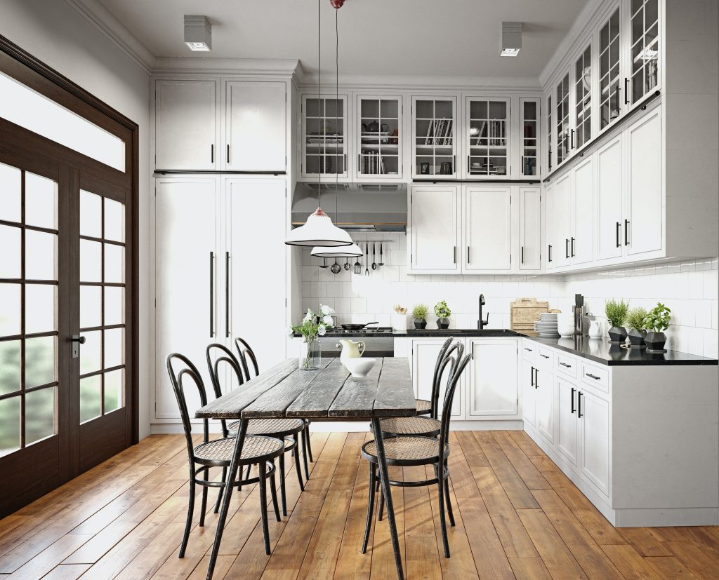 Large open kitchen with all white cabinets, hardwood floors, and stained large doors leading outside.