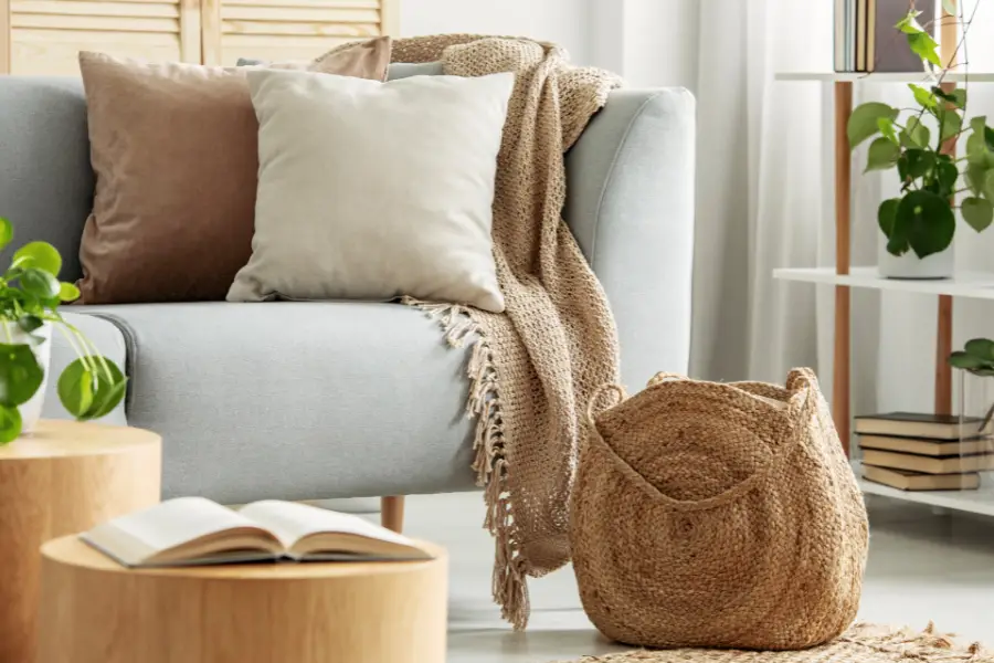 Sofa with a blanket, pillow, and pouf.