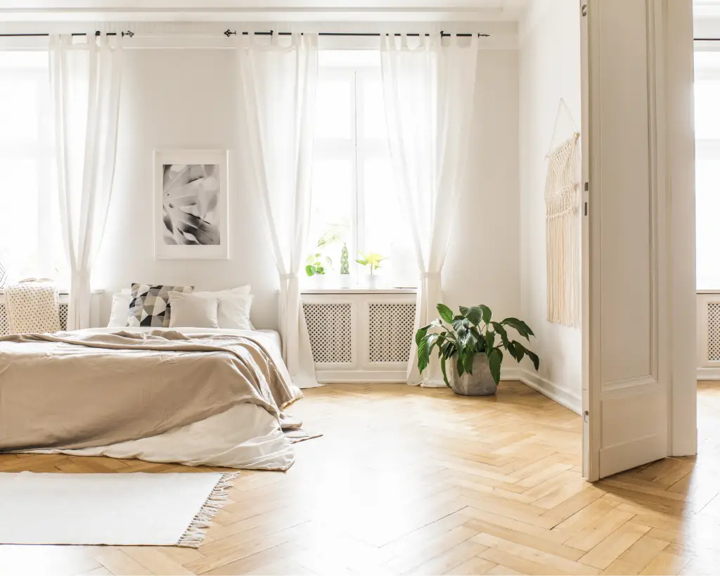 Bedroom with large windows and flowing curtains.