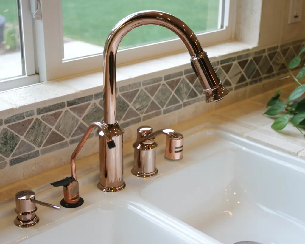 Gold faucet with tile backsplash in a kitchen.
