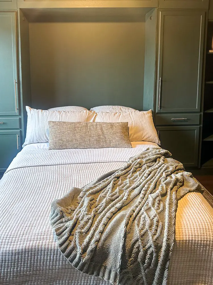 Murphy bed pulled down with beautiful bedding and a soft blanket draping over the end for Home Office Guest Room Reveal.