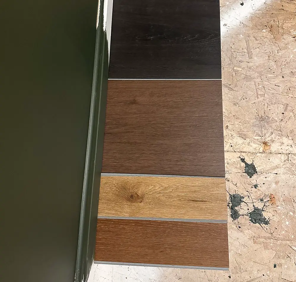 Flooring sample next to moody green wall.