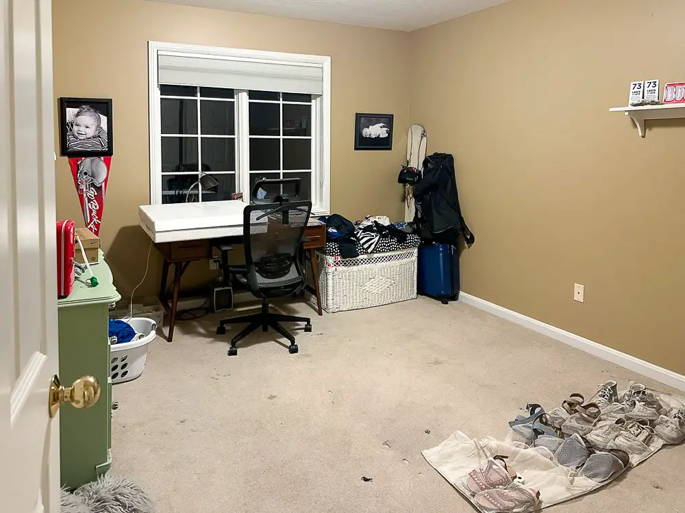 A spare bedroom painted tan with a hodge podge of stuff in it.