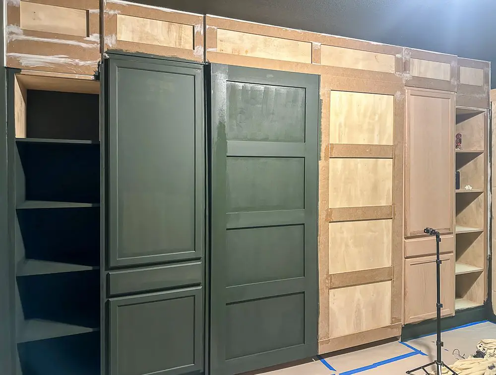 A wall of cabinets trimmed out and partially painted green.