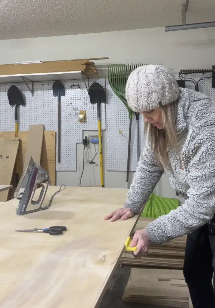 Girl trimming out a plywood panel with edge-banding.