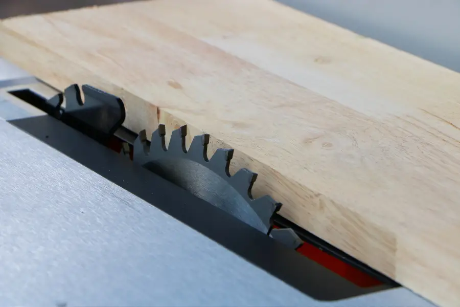 Dimensional piece of wood sliding through a table saw.