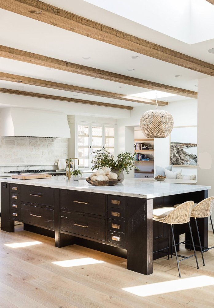 Beautiful all white kitchen with a black center island and wooden beams on the ceiling.