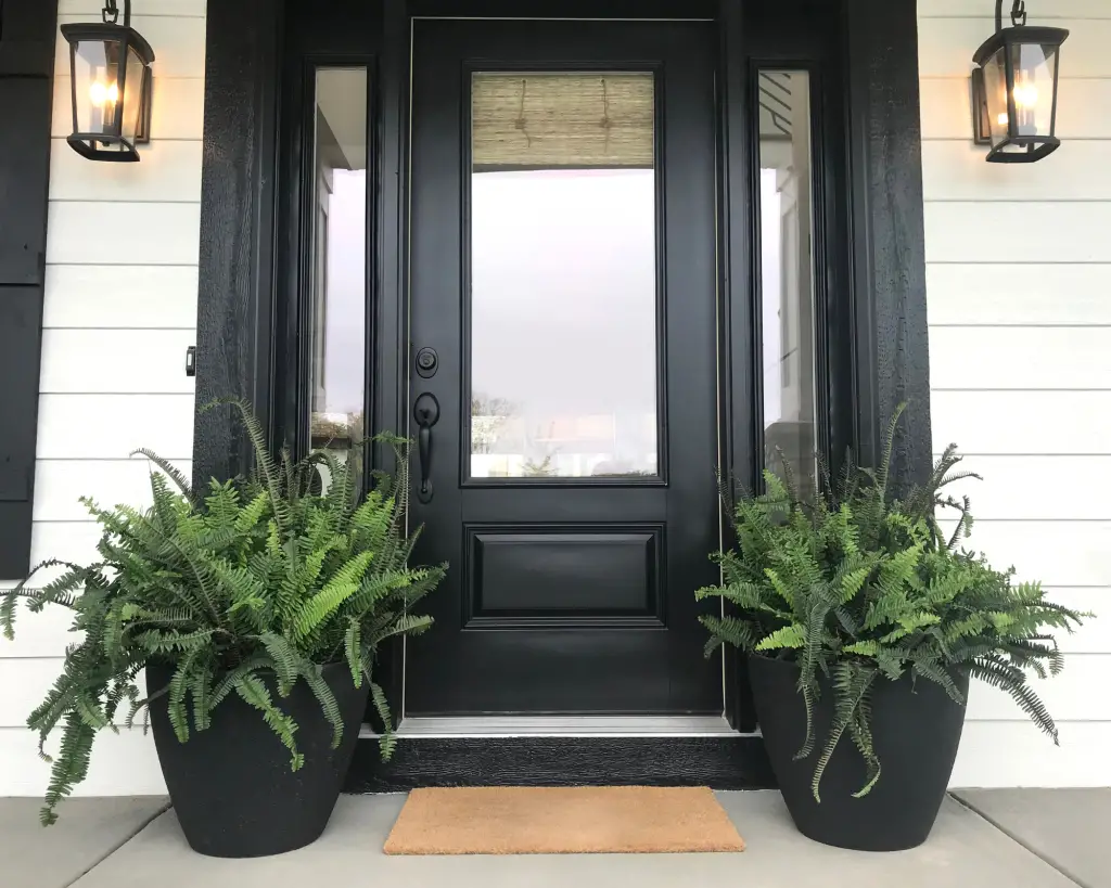 Front doormat in front of black doors.